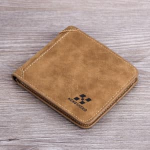 Portefeuille couleur camel carré posé sur une surface en bois. Il y a un logo noir en bas à droit du portefeuille.