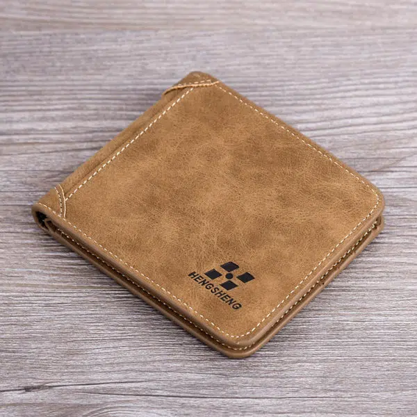 Portefeuille couleur camel carré posé sur une surface en bois. Il y a un logo noir en bas à droit du portefeuille.