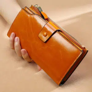 Grand portefeuille marron en cuir à zip tenu dans une main.