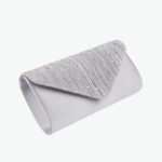 Pochette portefeuille argentée avec des paillettes sur le dessus. Fond gris avec des fleurs.