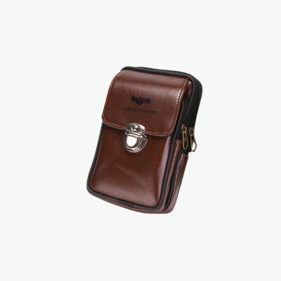 Deux portefeuilles marrons en cuir avec fermeture à boutons. Derrière se trouvent des livres blancs et noirs ainsi qu'une plante verte.