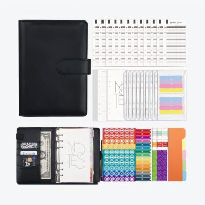 Portefeuille noir dans le coin gauche, avec les éléments qui le composent autour : agenda, stickers, et on voit le portefeuille ouvert