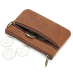 Petit portefeuille marron avec deux fermetures éclair sur fond blanc et avec des pièces.