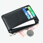 Petit portefeuille noir avec cartes, billets et pièces sur fond blanc.