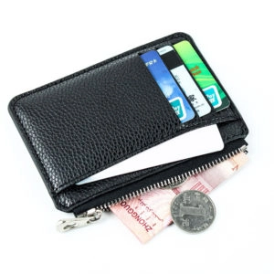 Petit portefeuille noir avec cartes, billets et pièces sur fond blanc.
