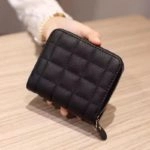 Mini portefeuille matelassé noir tenue par une main