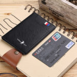portefeuille noir avec drapeau et écriture blanche, posé sur un carnet à côté d'une carte de crédit.
