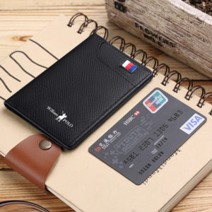 portefeuille noir avec drapeau et écriture blanche, posé sur un carnet à côté d'une carte de crédit.