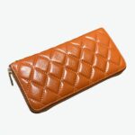 Portefeuille orange en cuir de vachette matelassé à zip pour femme.