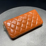 Portefeuille orange en cuir de vachette matelassé à zip pour femme.