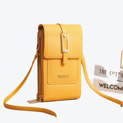 Superbe sac portefeuille jaune élégant et très féminin posé sur une table près de livres.