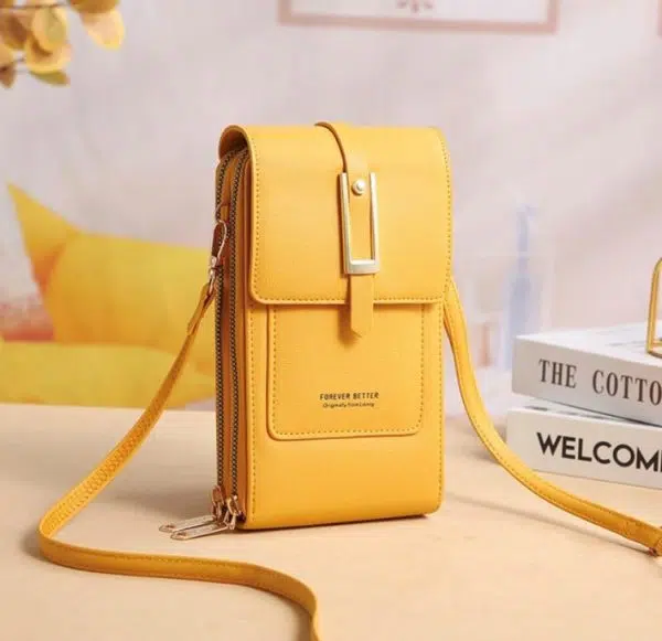 Superbe sac portefeuille jaune élégant et très féminin posé sur une table près de livres.