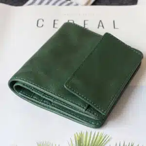 Portefeuille en cuir vert posé sur un magazine blanc