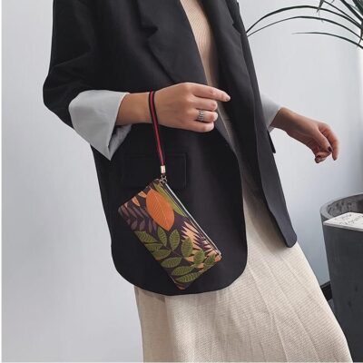 Femme en veste noir et jupe beige portant un petit sac marron avec des fleurs colorées