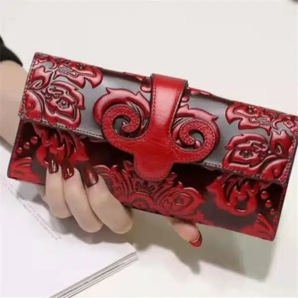 Portefeuille noir avec des fleurs rouges tenu par une main avec du vernis rouge